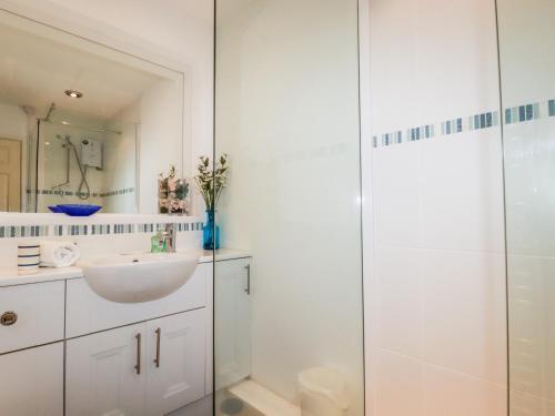 a white bathroom with a sink and a shower at Harlyn in Mevagissey