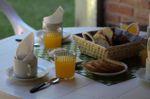 una mesa con vasos de zumo de naranja y una cesta de pan en La Palapa ApartHotel, en Villa General Belgrano