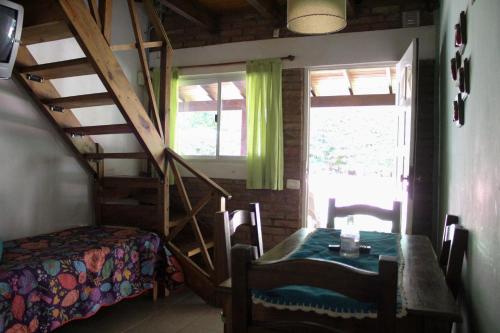 a room with a table and a staircase and a bed at La Palapa ApartHotel in Villa General Belgrano