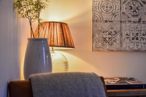 a lamp and a vase on a table next to a chair at The Malthouse - Naturally styled central apartment in Cirencester