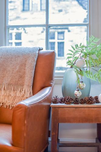a chair and a table with a plant and a window at The Malthouse - Naturally styled central apartment in Cirencester
