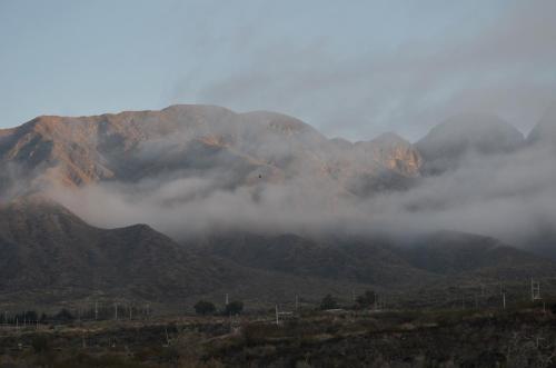 a mountain covered in fog and clouds in the mountains at Cabañas swissminiatur in Cacheuta