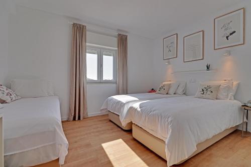 a white bedroom with two beds and a window at SEA SALT SAGRES APARTMENT in Sagres