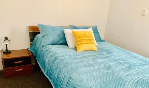 a bed with blue and yellow pillows on it at Auckland Central Motel in Auckland
