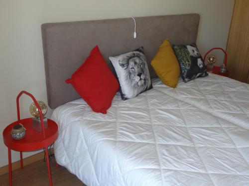 een bed met kleurrijke kussens erop bij Pé No Mar Apartment in Vila do Conde