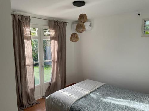 a bedroom with a bed and a window at Magnifique Villa Domaine de Biglette in Baie-Mahault