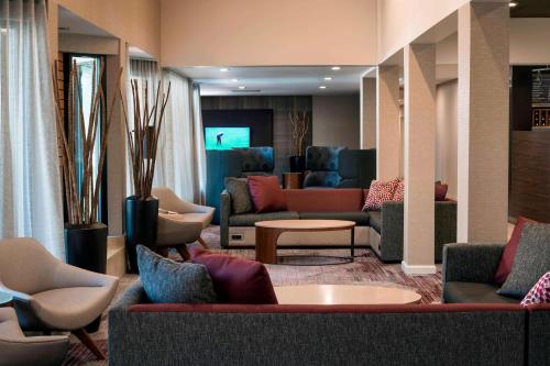 a lobby with couches and chairs and a television at Sonesta Select Los Angeles Torrance South Bay in Torrance
