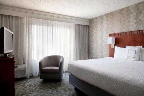 a hotel room with a bed and a chair and a television at Sonesta Select Los Angeles Torrance South Bay in Torrance