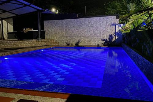 una piscina con iluminación azul en un patio trasero por la noche en Aguamarina Inn - Casa de descanso con piscina - Tauramena Casanare en Tauramena