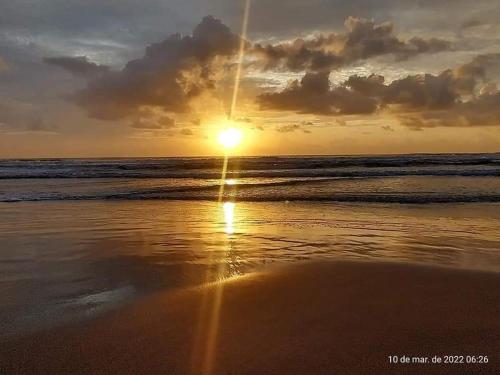 a sunset on a beach with the ocean at Apartamento encantador na praia de Navegantes in Navegantes