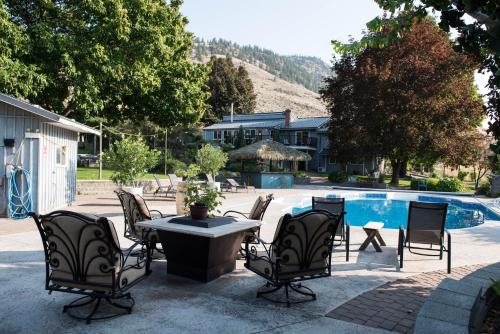 un patio con sillas y una mesa junto a la piscina en Similkameen Wild Resort & Winery Retreat, en Cawston