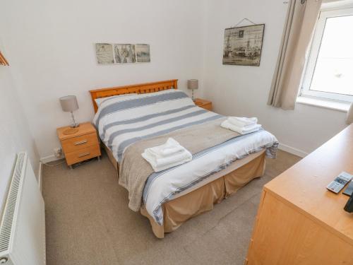 a bedroom with a bed with two towels on it at The Beach House in Llanelli