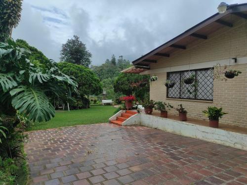 a brick walkway in front of a house with potted plants at Hermosa finca villajovi con piscina privada in Cali