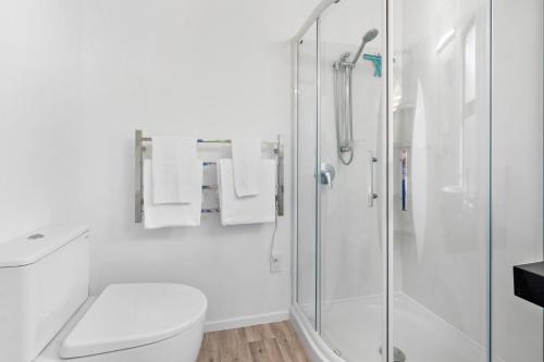a white bathroom with a shower and a toilet at Acacia Heights - Garden Cottage - Taupo in Taupo