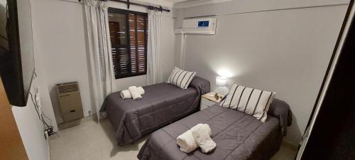 Cette petite chambre comprend 2 lits et une fenêtre. dans l'établissement Departamento 1A Santiago del Estero 80, à Salta