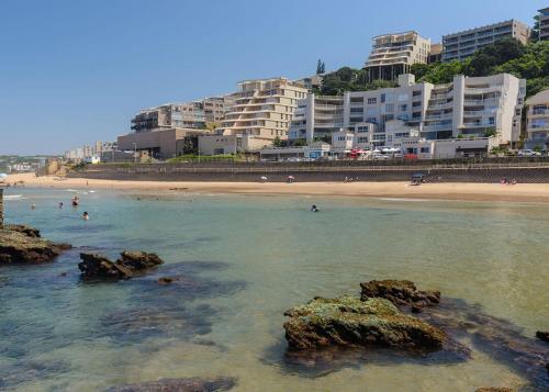 a beach with people in the water and buildings at Petfriendly, Umdloti Beachfront Escape in Umdloti
