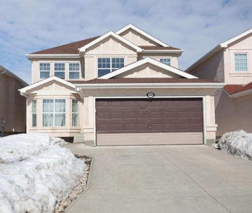 a house with a garage door in the snow at Elegant 6 Bedroom House Near U of Manitoba in Winnipeg