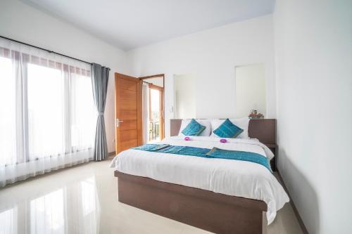 a white bedroom with a large bed with blue pillows at Umah Odah Homestay in Ubud