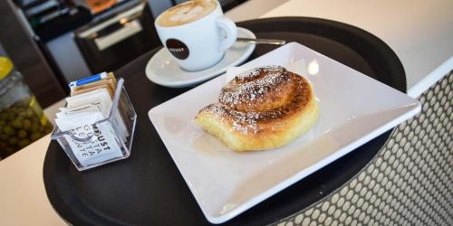 un pastel en un plato en una mesa con una taza de café en Dimora Santa Caterina, en Altamura