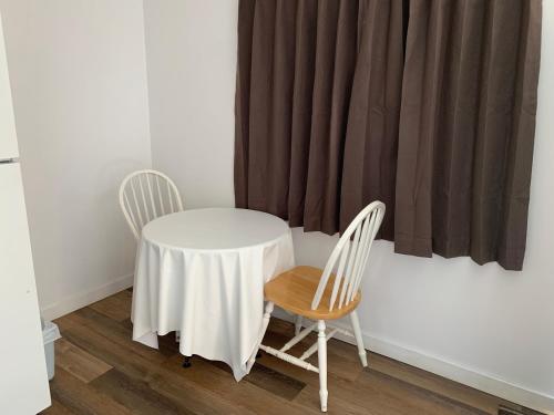 a table and two chairs in a room with a curtain at Swiss Sunset Inn in Penticton