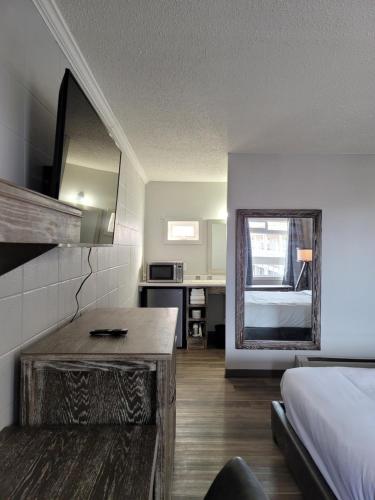 een slaapkamer met een bed, een bureau en een spiegel bij Parkside Inn in Grande Prairie
