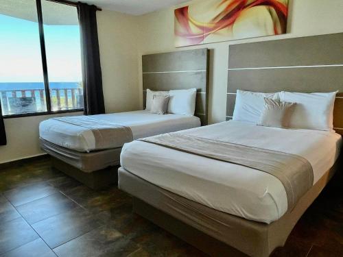 a hotel room with two beds and a large window at Hotel El Guajataca in Quebradillas