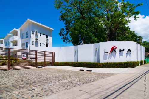 a white wall with a la agency sign on it at Jaco Modern & Beach Apartment - Lapa Living A1 in Jacó
