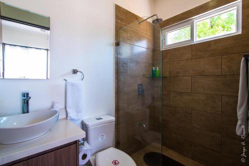 a bathroom with a toilet and a sink and a shower at Jaco Modern & Beach Apartment - Lapa Living A1 in Jacó