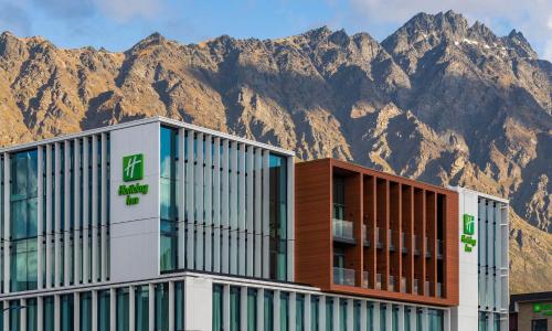 a building with a mountain in the background at Holiday Inn Queenstown Remarkables Park in Queenstown