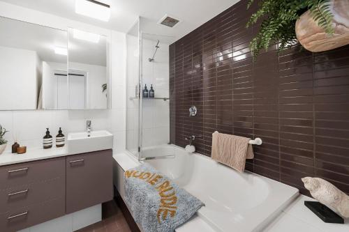 a bathroom with a tub and a sink and a mirror at Lorne Chalet Apartment 33 in Lorne