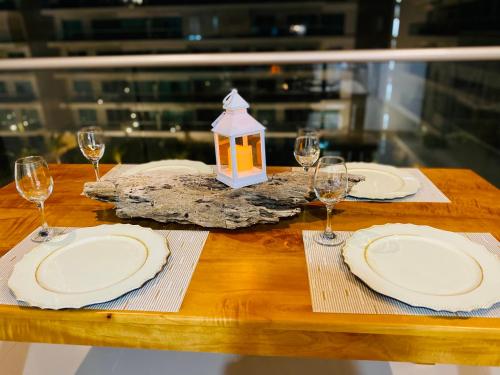 a wooden table with white plates and wine glasses at morros epic luxury in Cartagena de Indias