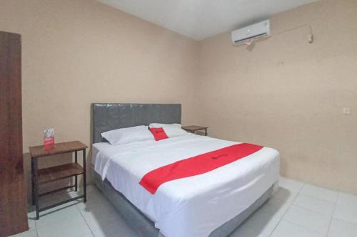 um quarto com uma grande cama branca e um cobertor vermelho em RedDoorz @ Waena Jayapura em Sentani