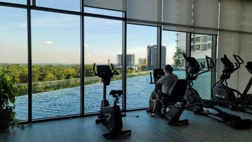 a man exercising in a gym with a view of the water at Macrolink Medini by RR JBcity in Nusajaya