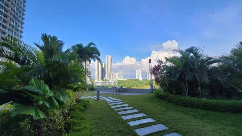 a pathway in a park with palm trees and buildings at Macrolink Medini by RR JBcity in Nusajaya