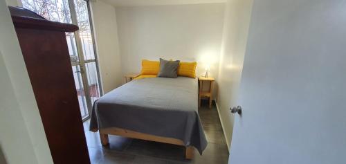 um quarto com uma cama com almofadas amarelas e uma janela em Bogotá hermoso departamento en CDMX em Cidade do México