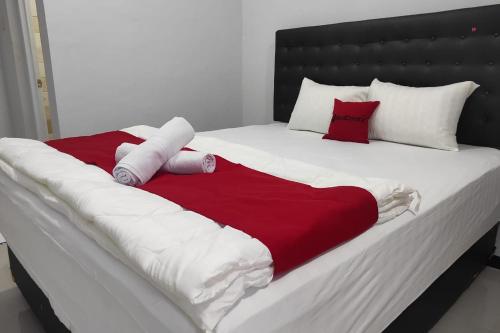 Una cama grande con una manta roja y blanca. en RedDoorz Syariah near Alun Alun Purwokerto 2 en Purwokerto