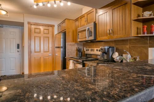 a kitchen with wooden cabinets and a granite counter top at Incredible Mountain View Townhouse in DT Canmore w/ A/C & U/A Parking in Canmore
