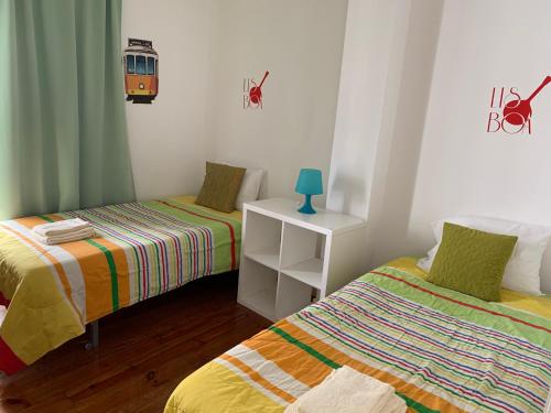 Cette chambre comprend deux lits et une table avec une lampe. dans l'établissement GuestHouse Pena, à Lisbonne