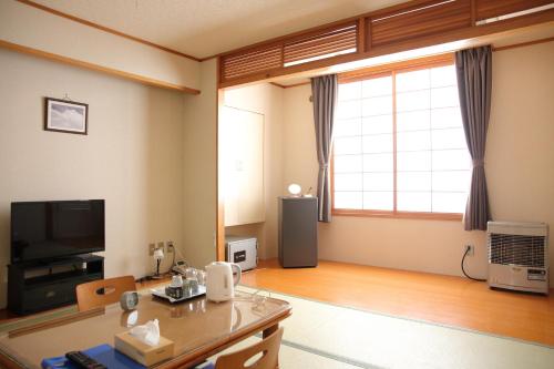 een woonkamer met een tafel en een groot raam bij ピンネシリ温泉望岳荘 