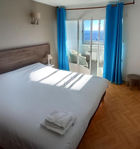 - une chambre dotée d'un grand lit avec des rideaux bleus dans l'établissement Trois appartements secteur FONCILLON PLAGE, à Royan
