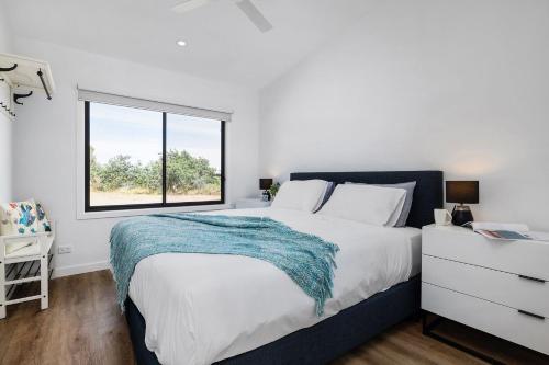 a white bedroom with a large bed and a window at Banksia Villa in Eganstown