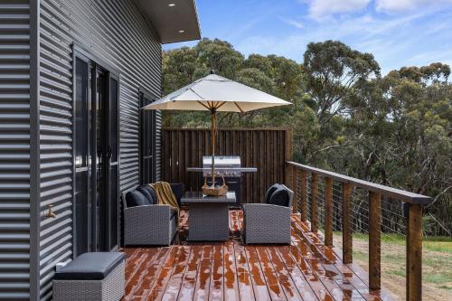 a deck with a table and chairs and an umbrella at Banksia Villa in Eganstown