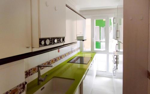a kitchen with green and white counter tops at Apartamento con piscina y WIFI a 100 metros de la playa en Somo in Somo