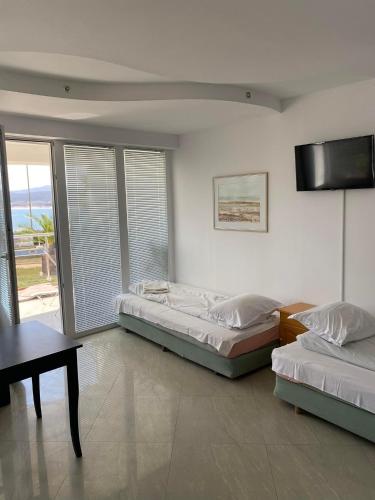 a bedroom with two beds and a table and a television at Safo Apartments and Rooms in Sozopol