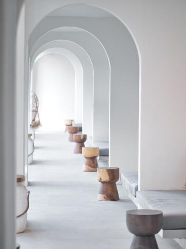 a row of wooden stools in a white hallway at El Tropico Boutique Hotel in Kuta Lombok