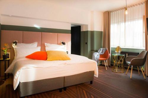a hotel room with a bed with orange and yellow pillows at Hotel Neuer Fritz in Berlin