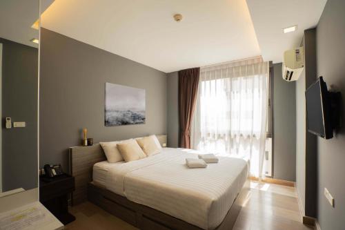 a bedroom with a large bed with white sheets and a window at Dazzle Residence in Bangkok