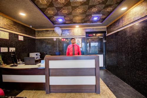 a man standing behind a counter in a restaurant at OYO Hotel Grand Akshay in Jaipur