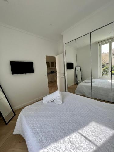 une chambre blanche avec un grand lit et un miroir dans l'établissement amazing new property in the heart of the old town of antibes, à Antibes