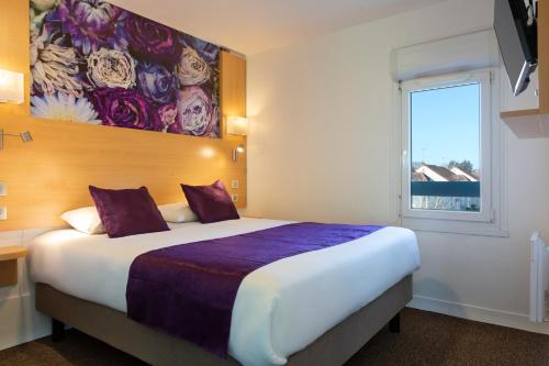 a hotel room with a large bed and a window at Fasthotel Orleans Zénith in Orléans